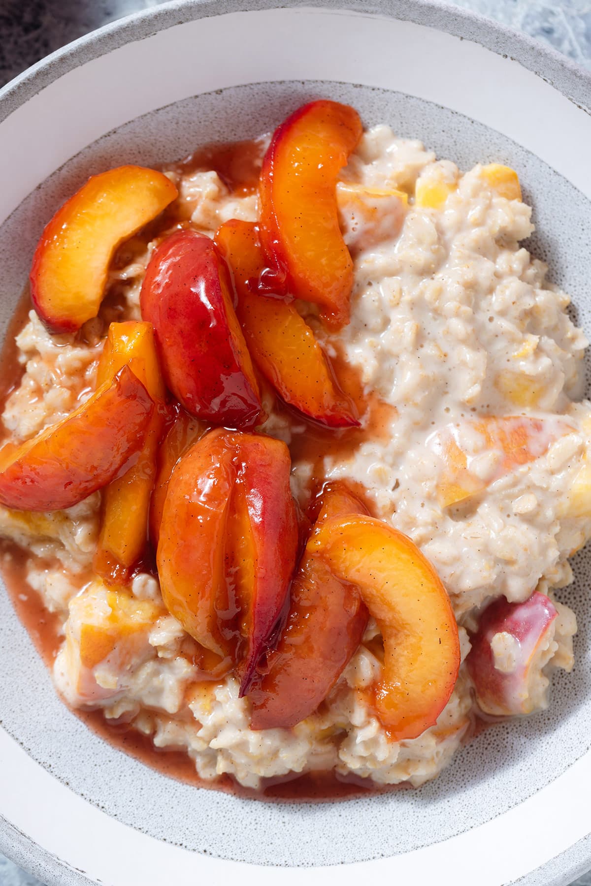 Peach oatmeal with caramelized peaches on top in a a grey bowl.