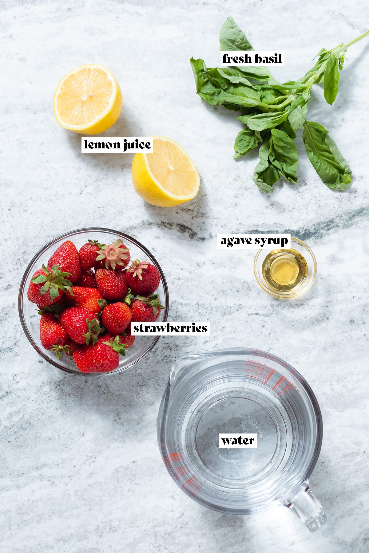 Ingredients like strawberries, basil, lemon, and water on a grey stone background with text overlay.