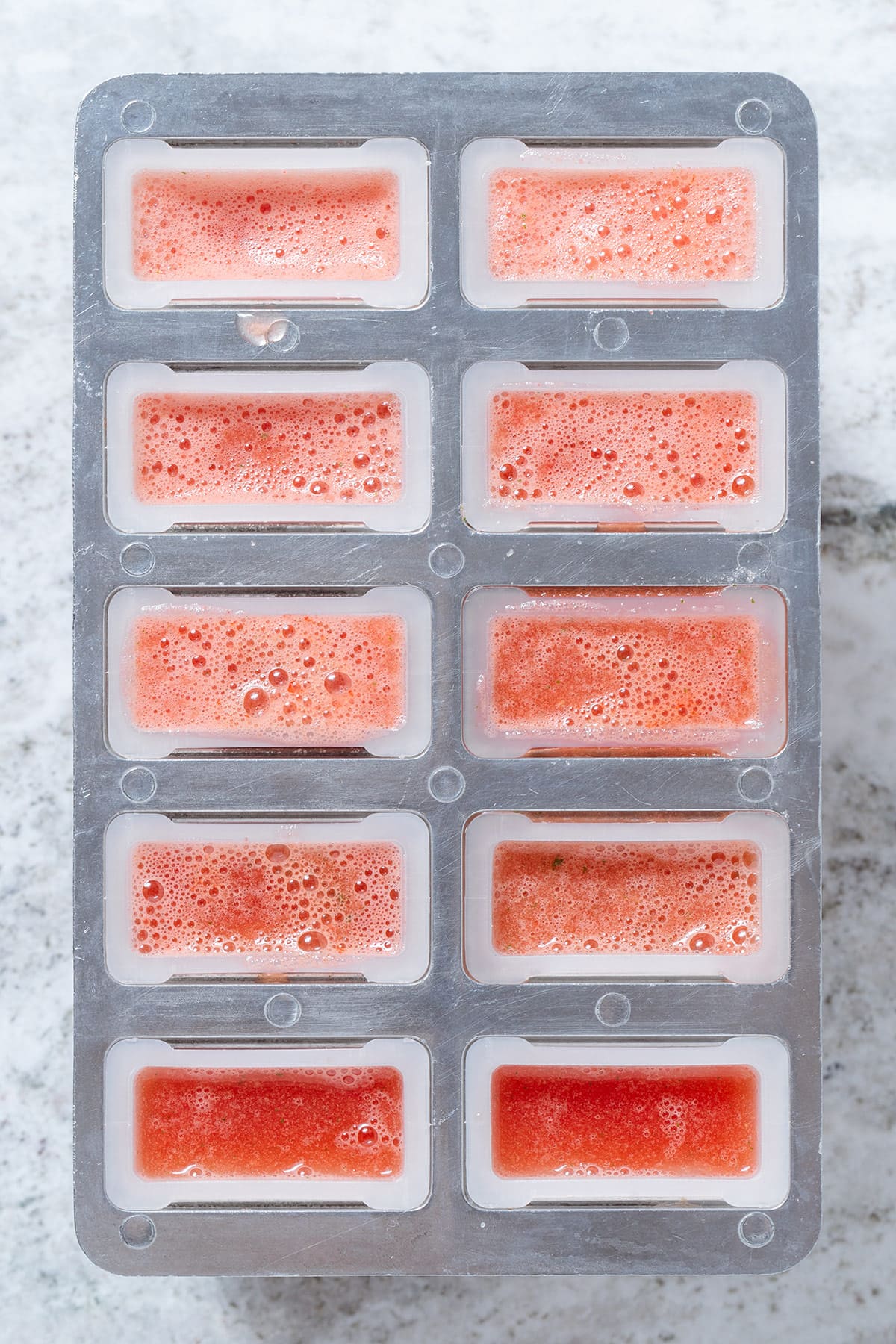 Blended watermelon in popsicle molds before freezing.