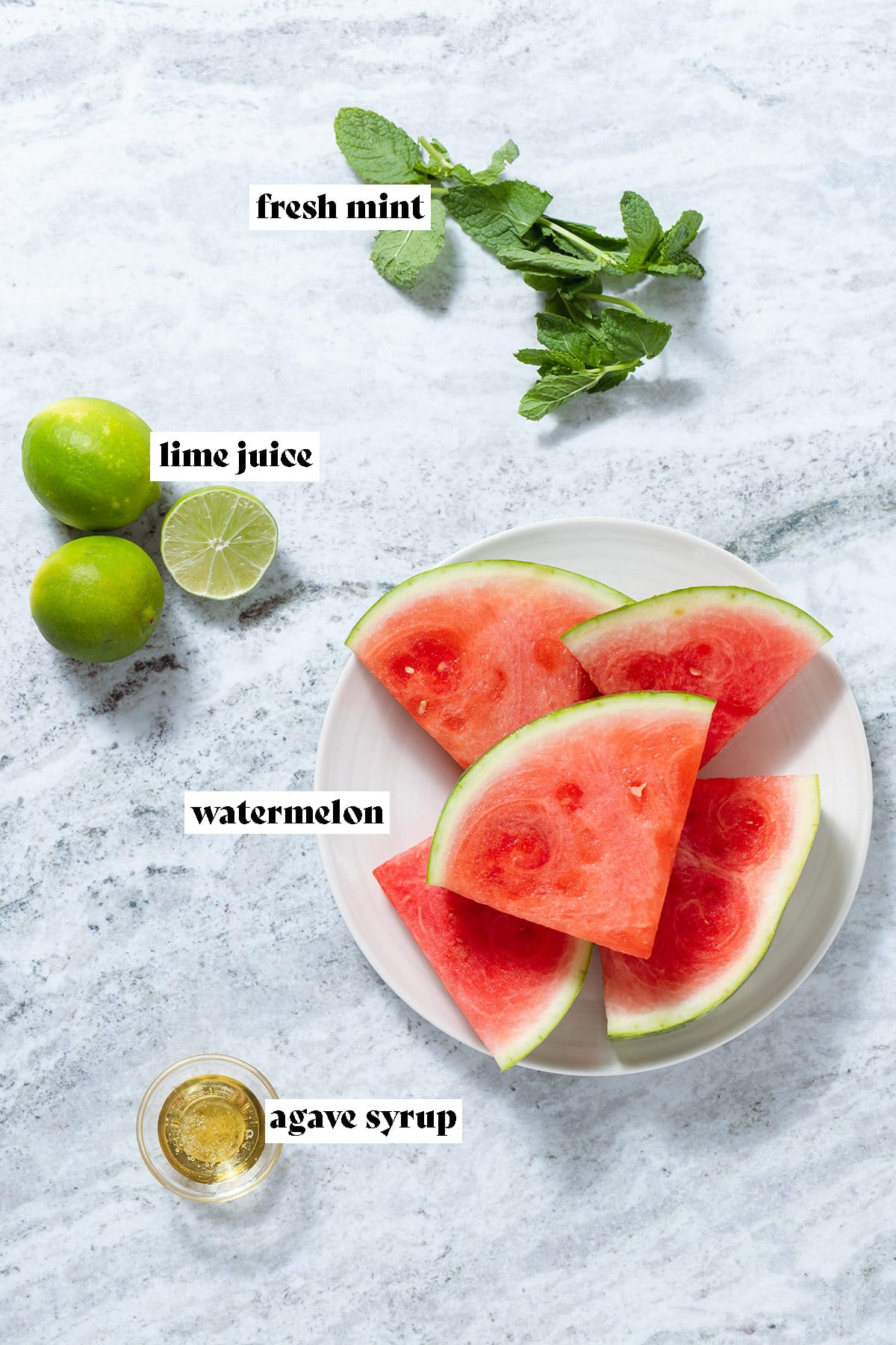 Slices of watermelon, fresh mint, lime, and agave laid out on grey stone background with text overlay.