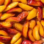 Caramelized peaches in a large steel pan.