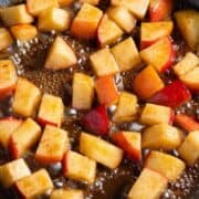 Diced apples simmering with butter and maple syrup in a non-stick pan.