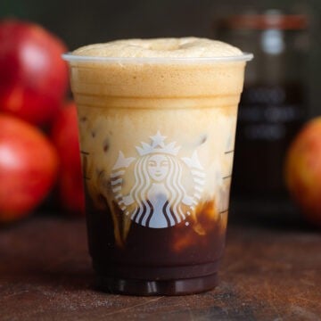 Shaken espresso in a plastic Starbucks cup with oat milk on top slowly sinking to the bottom.