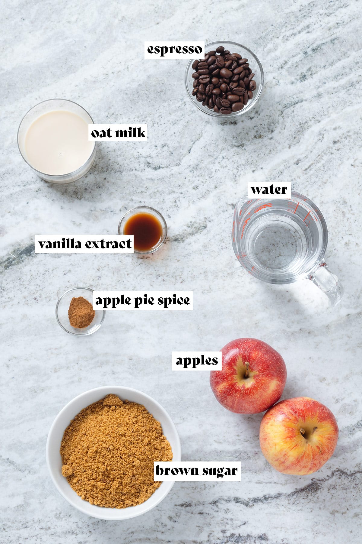 Apples, brown sugar, coffee beans, spices, and other ingredients laid out on a grey stone background with text overlay.