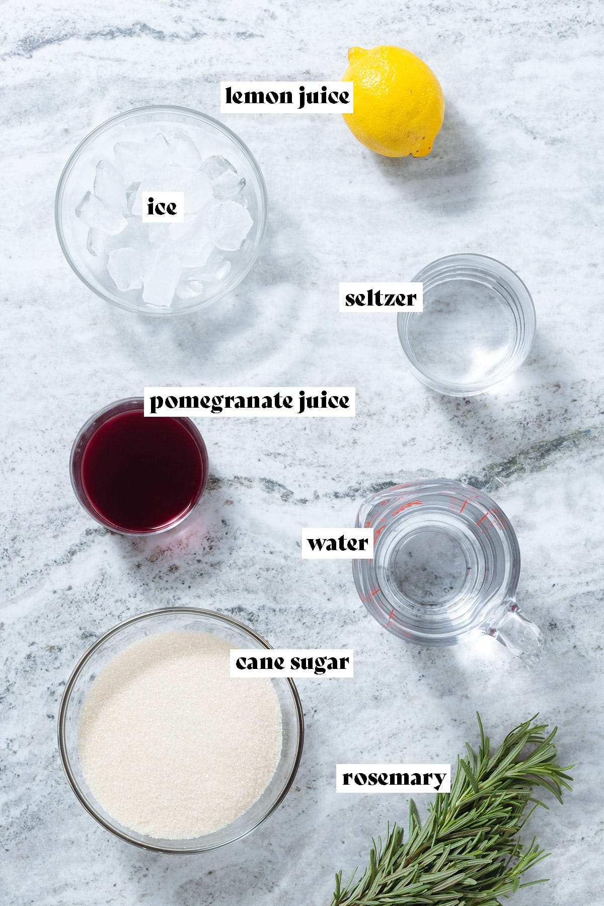 Rosemary, pomegranate juice, cane sugar, lemon, water, and seltzer laid out on a grey stone background with text overlay.