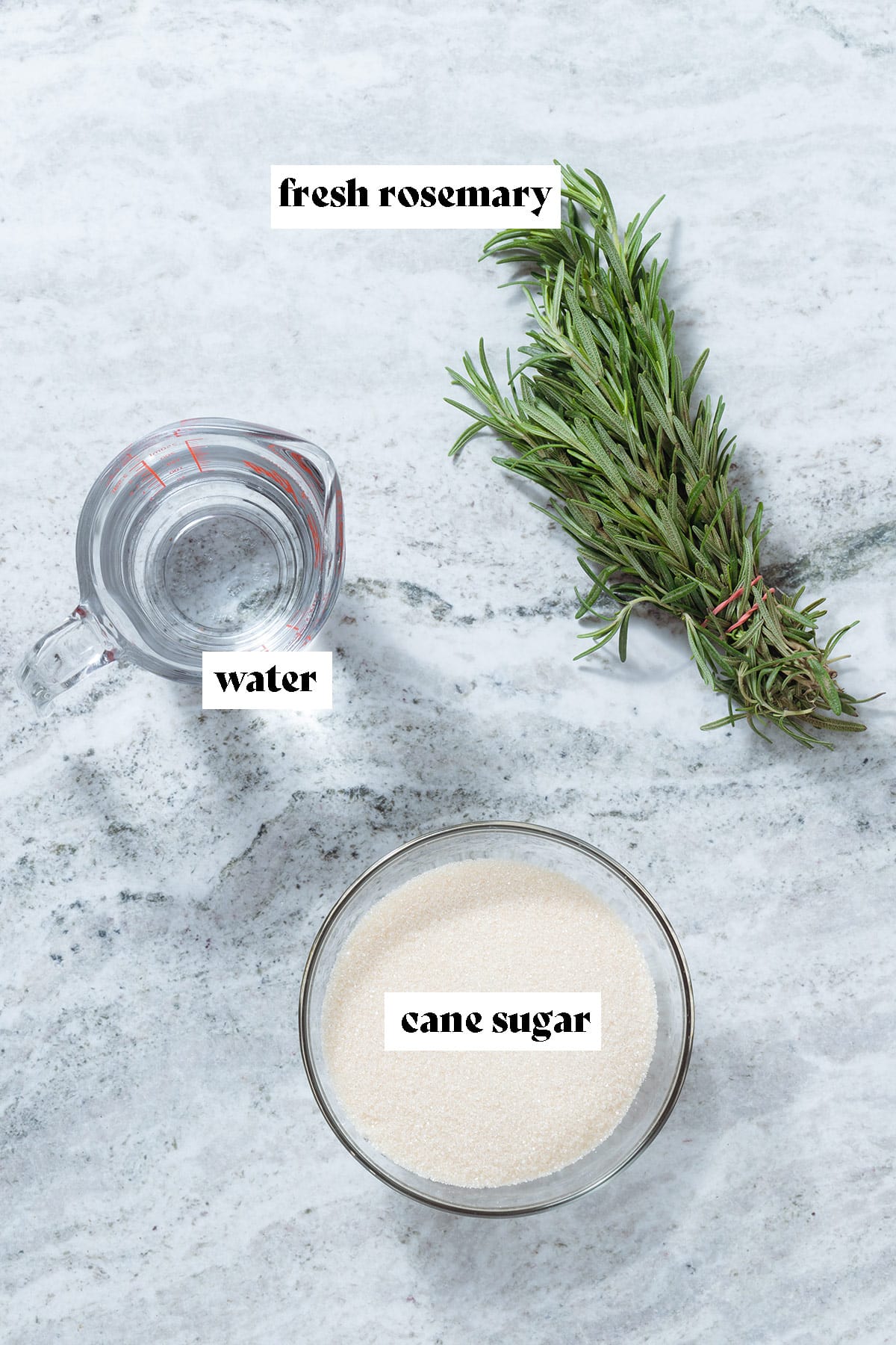 Cane sugar, fresh rosemary, and water on a grey stone background with text overlay.