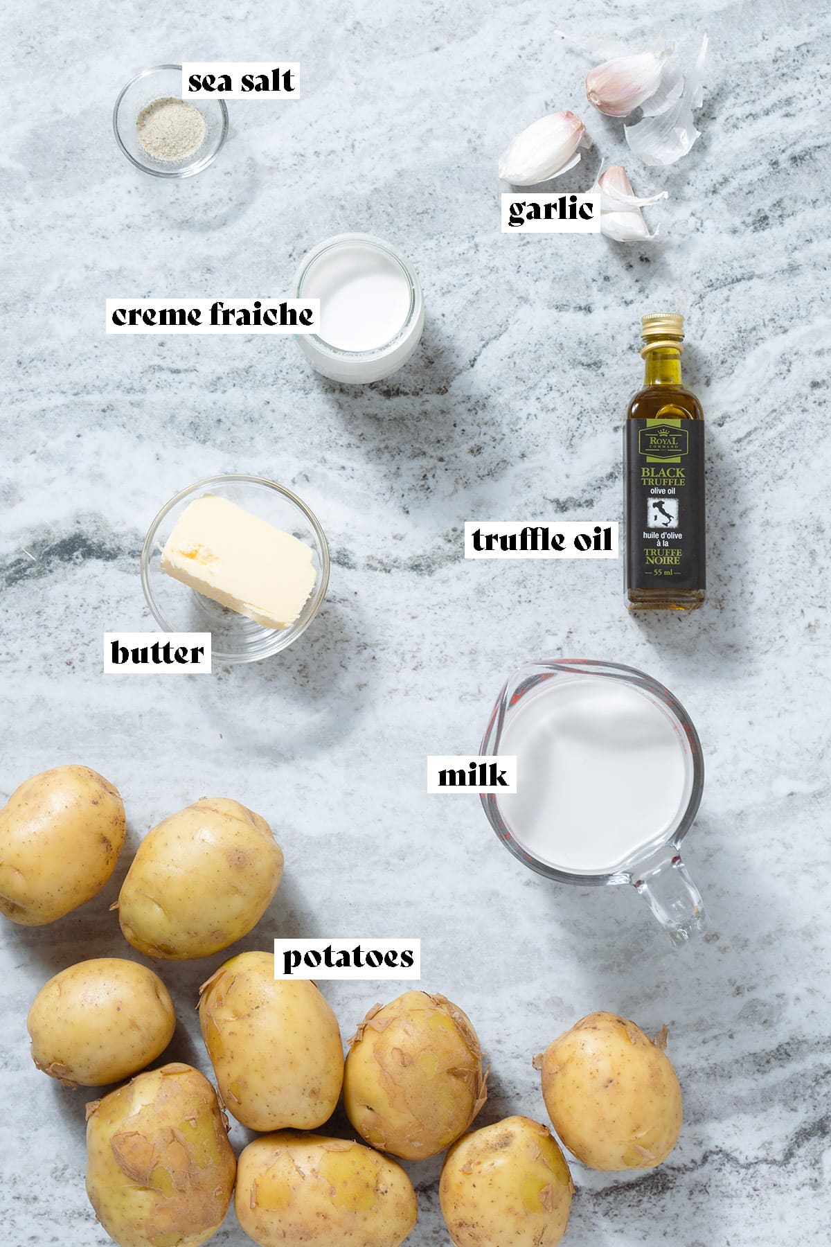 Potatoes, milk, truffle oil, butter, and other ingredients laid out on a grey stone background with text overlay.