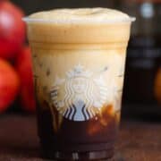 Shaken espresso in a plastic Starbucks cup with oat milk on top slowly sinking to the bottom.