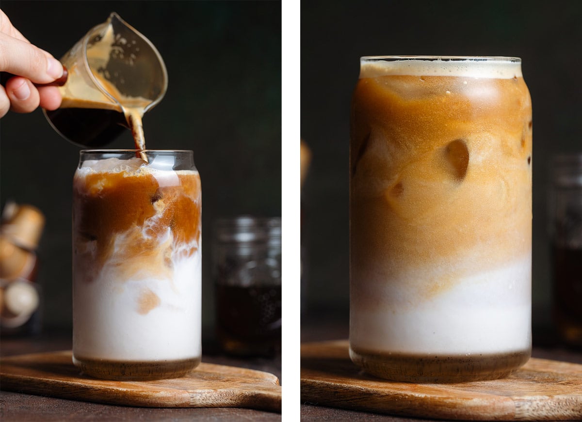 Coffee being poured into a glass with ice and milk and the coffee slowly mixing in with the milk.