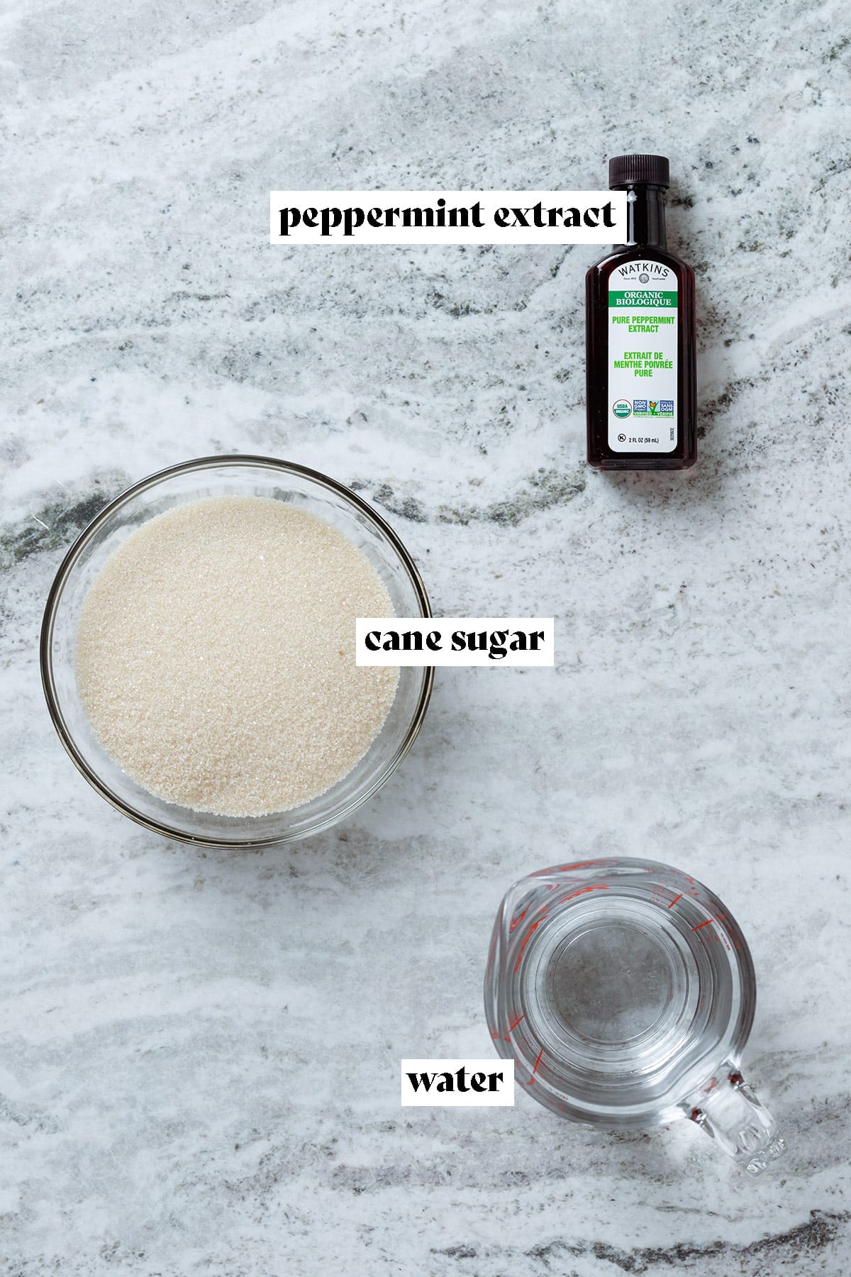 Peppermint extract, cane sugar, and water in bowls laid out on a grey background with text overlay.
