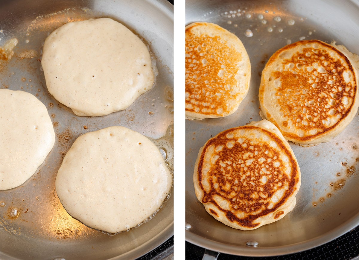Pancakes cooking in a large stainless steel pan with butter.