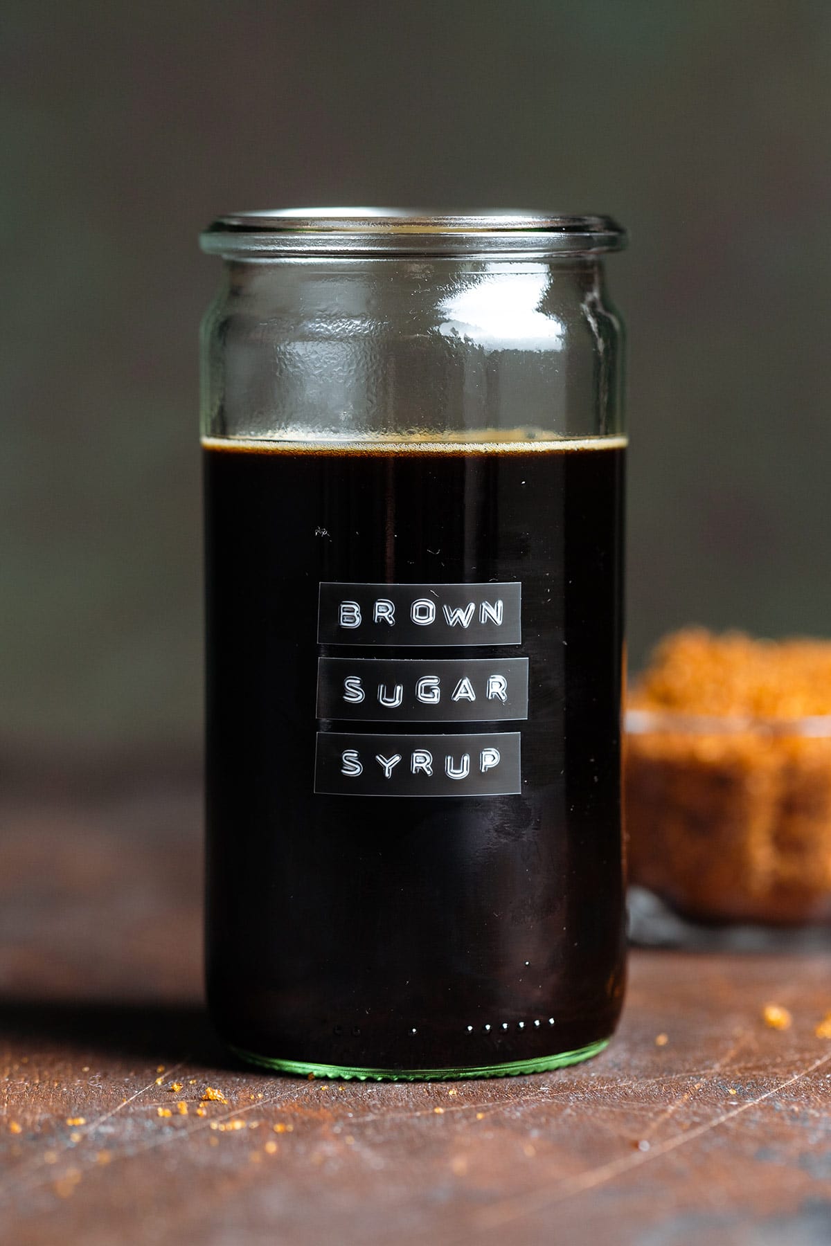 Dark syrup in a glass jar with an embossed label that say brown sugar simple syrup.