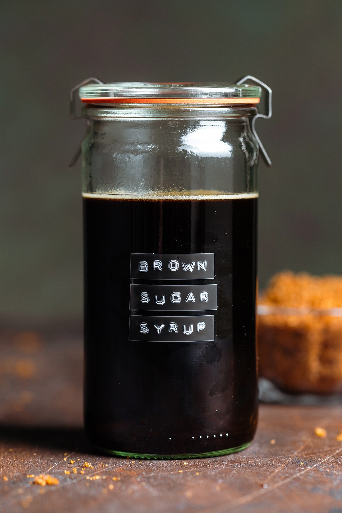 Dark syrup in a glass jar with a lid and an embossed label that say brown sugar simple syrup.