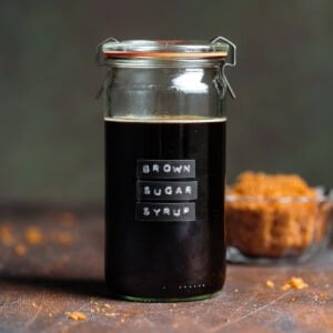 Dark syrup in a glass jar with a lid and an embossed label that say brown sugar simple syrup.