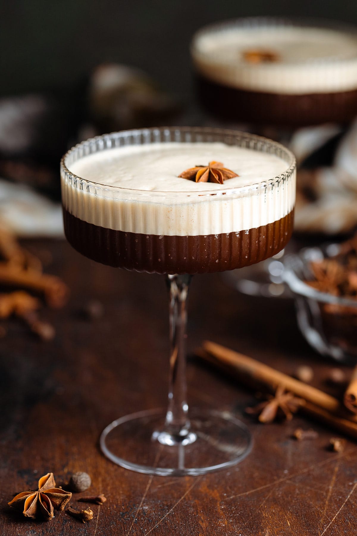 Chai espresso martini in a coupe glasses with a thick foam on top garnished with whole star anise.