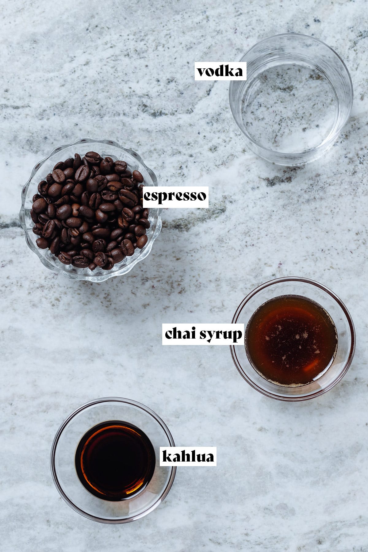 Coffee beans, vodka, maple syrup, and Kahlua all measured out in small bowls with text overlay.