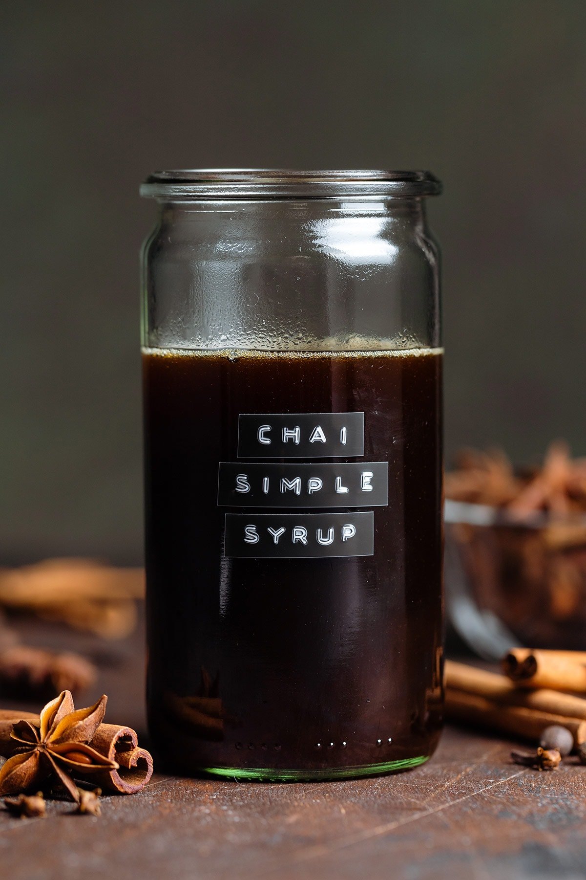 Dark syrup in a glass jar with a glass lid and an embossed label that say chai simple syrup.