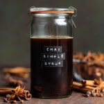 Dark syrup in a glass jar with a glass lid and an embossed label that say chai simple syrup.