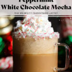 White chocolate mocha in a glass mug with whipped cream on top being sprinkled with crushed candy canes with more whole candy canes and Christmas ornaments in the background.