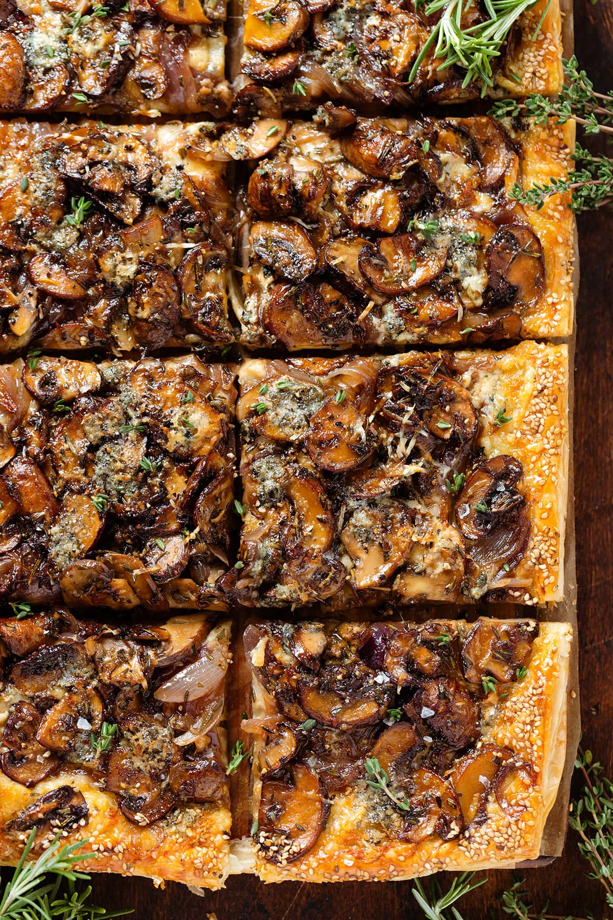 Baked puff pastry mushroom tart sliced into squares on a wooden cutting board.