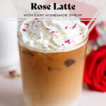 Iced latte with whipped cream and crushed dried rose petals sprinkled on top with a glass straw.