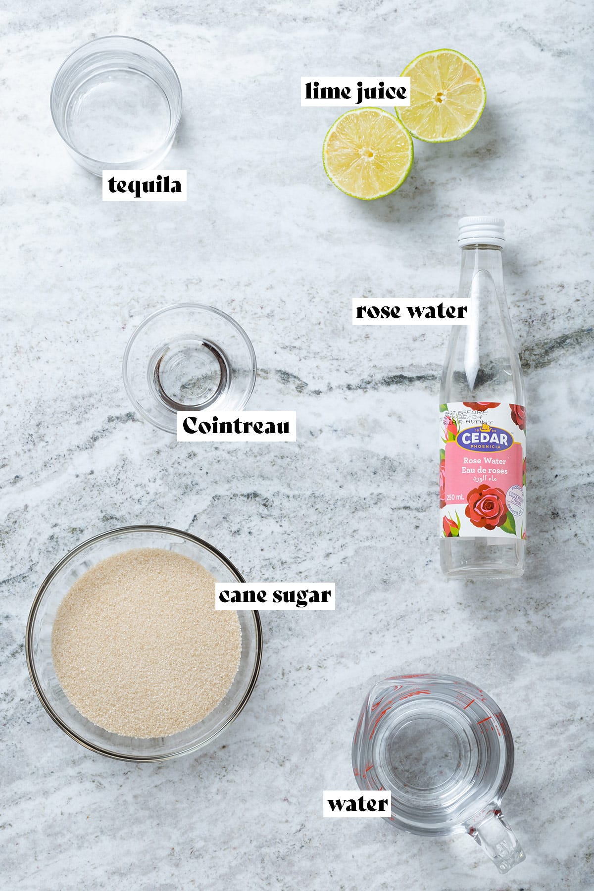 Cane sugar, rose water, cane sugar, water, lime, tequila, and Cointreau all measured and laid out with text overlay.