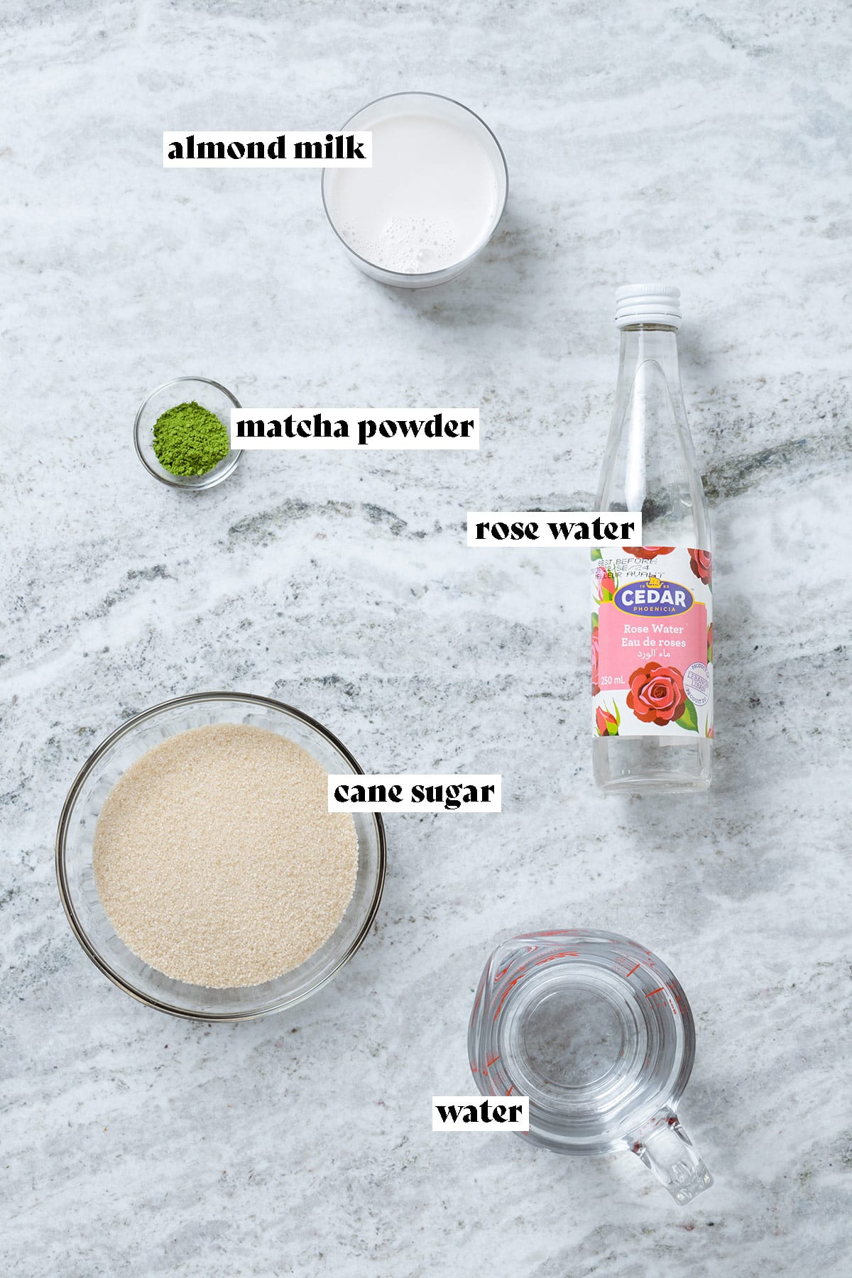 Cane sugar, matcha powder, milk, water, and rose water all measured and laid out with text overlay.