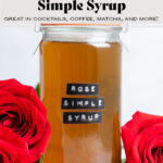 Light orange syrup in a glass jar with red roses around it with a label that saxs rose simple syrup.