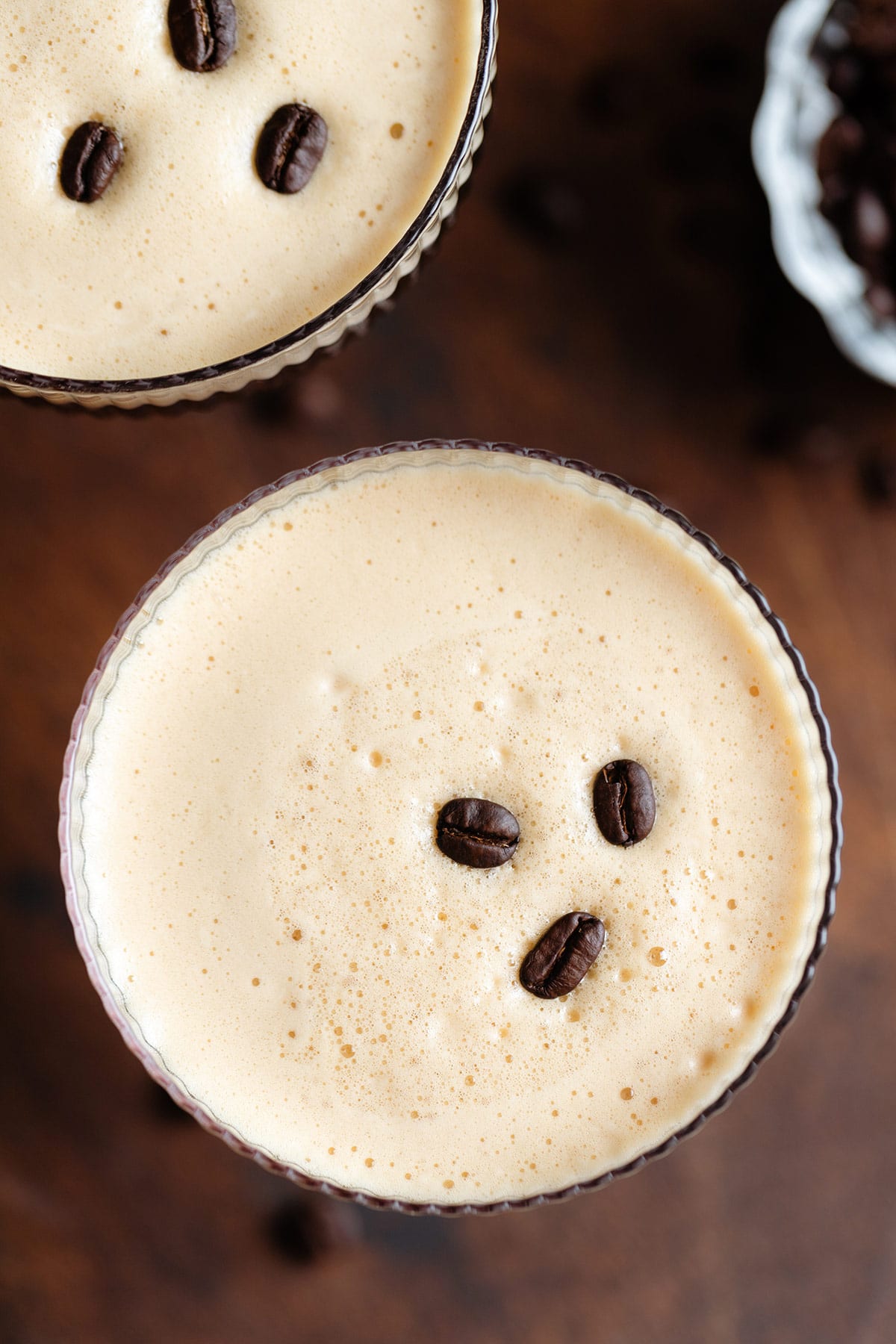 Espresso martini in a wide glass from above with only the foam visible garnished with three coffee beans.