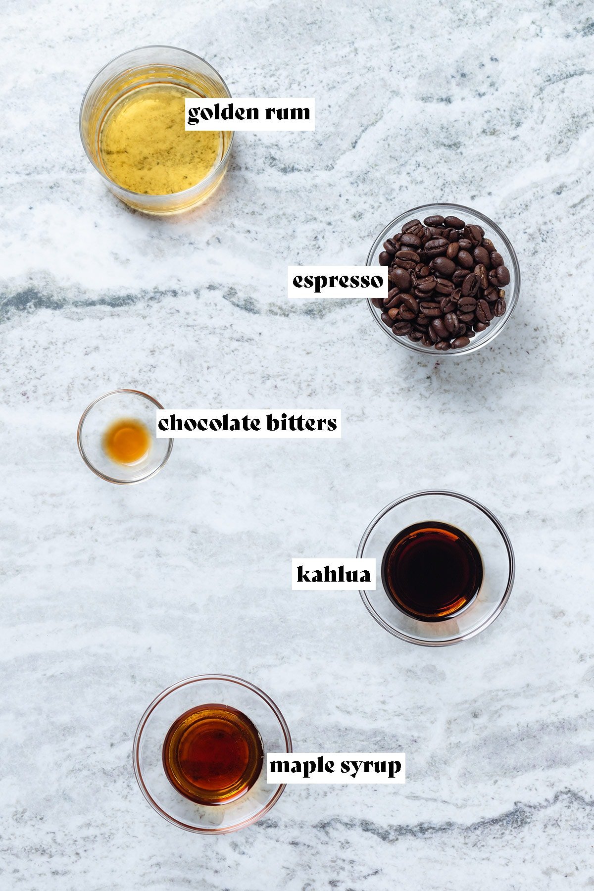 Rum, Kahlua, maple syrup, bitters, and espresso beans in small glass bowls with text overlay.