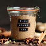 Chai spice mix in a glass jar with a black embossed label on the side.