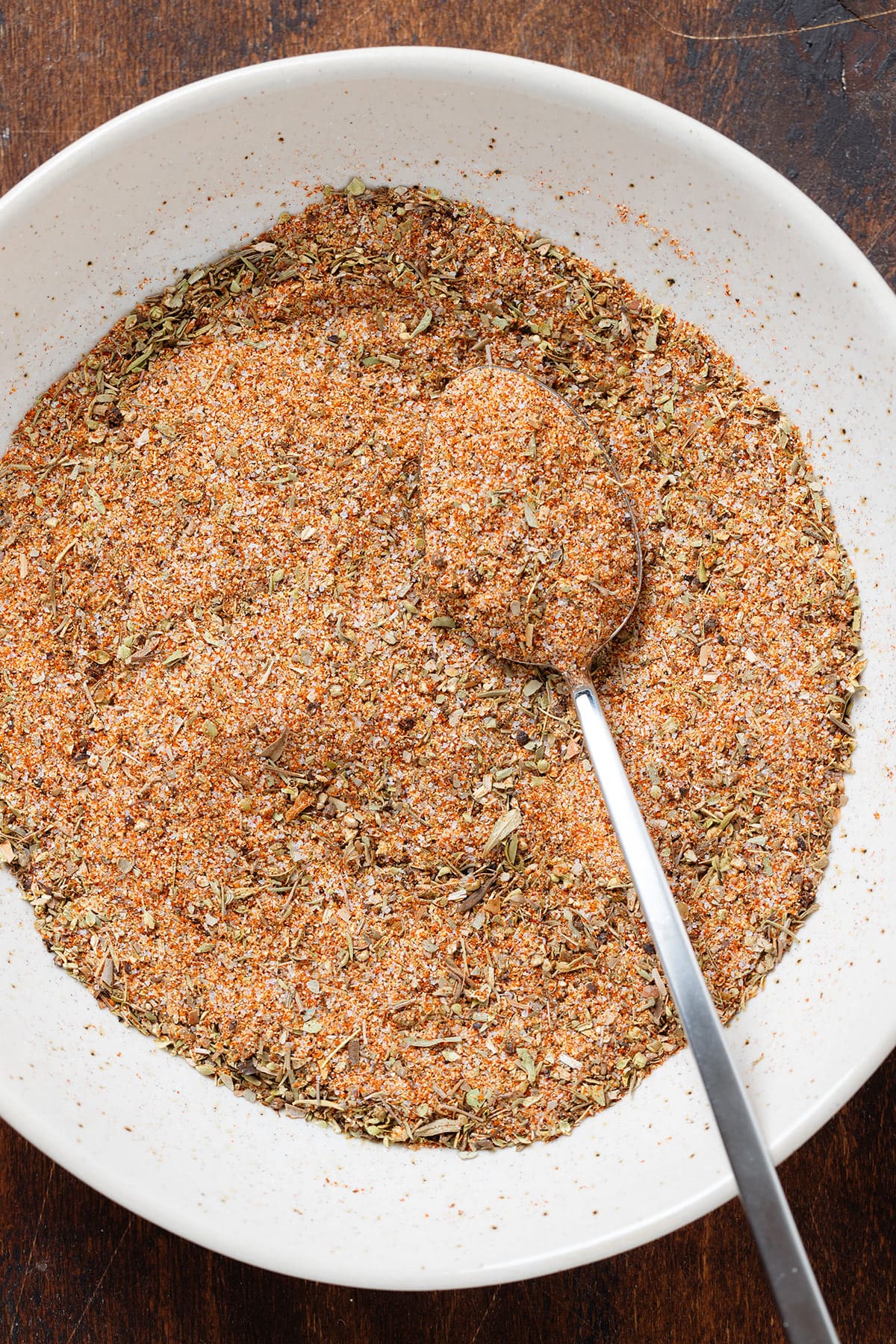 French fry seasoning all mixed together in a low bowl with a spoon on the right side.