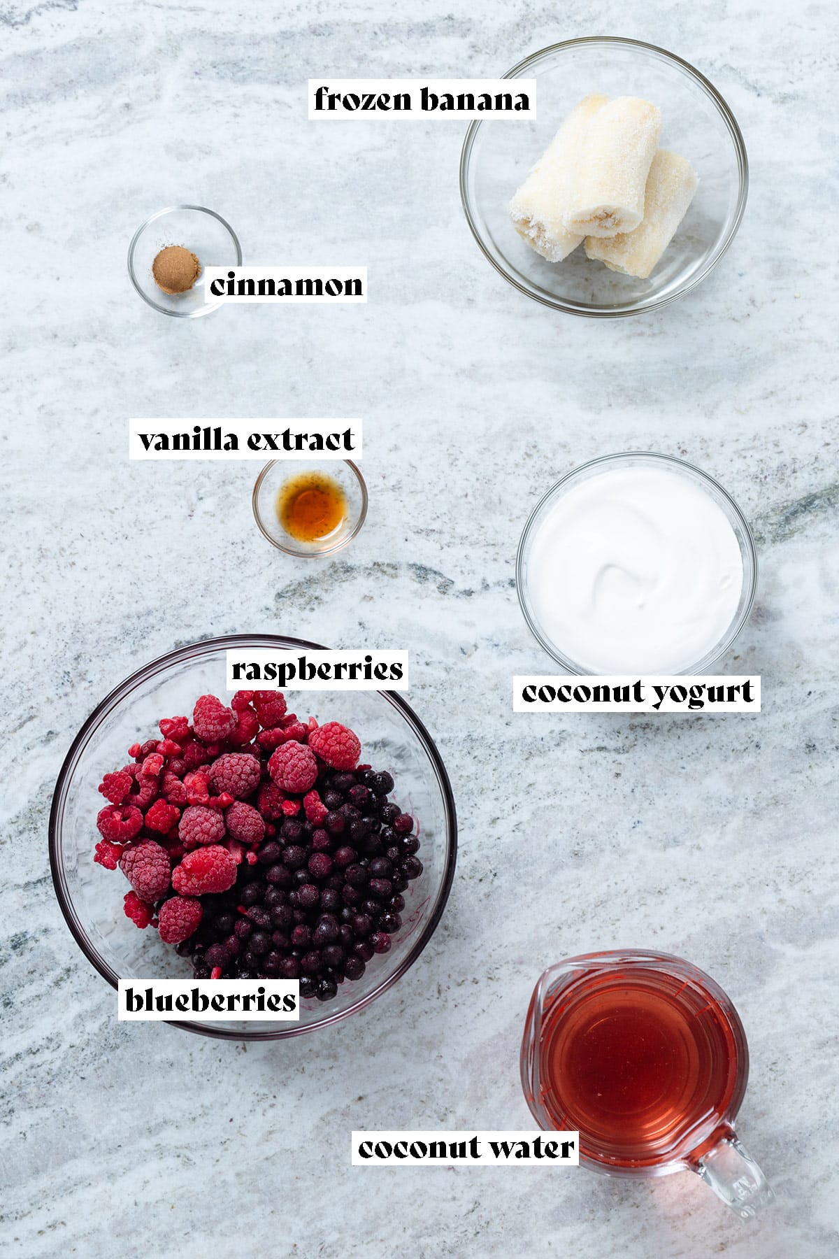 Ingredients like raspberries, blueberries, yogurt, and banana laid out on a grey stone background with text overlay.