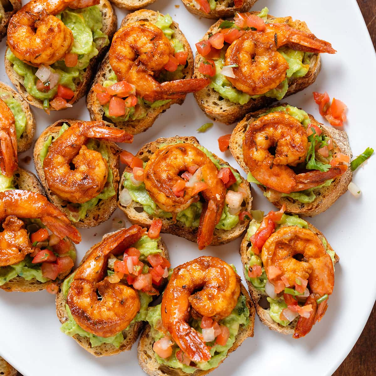Toasted baguette slices topped with guacamole, pico de gallo, and shrimp.