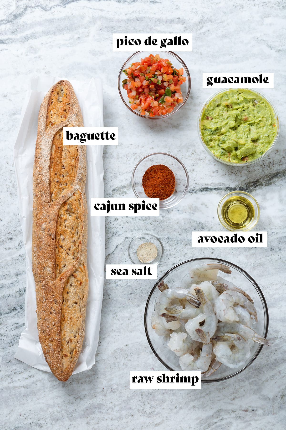Baguette, raw shrimp, guacamole, fresh salsa, and spices laid out on a grey stone background with text overlay.