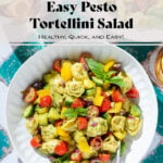 Tortellini pesto salad with fresh chopped veggies and basil in a white bowl.