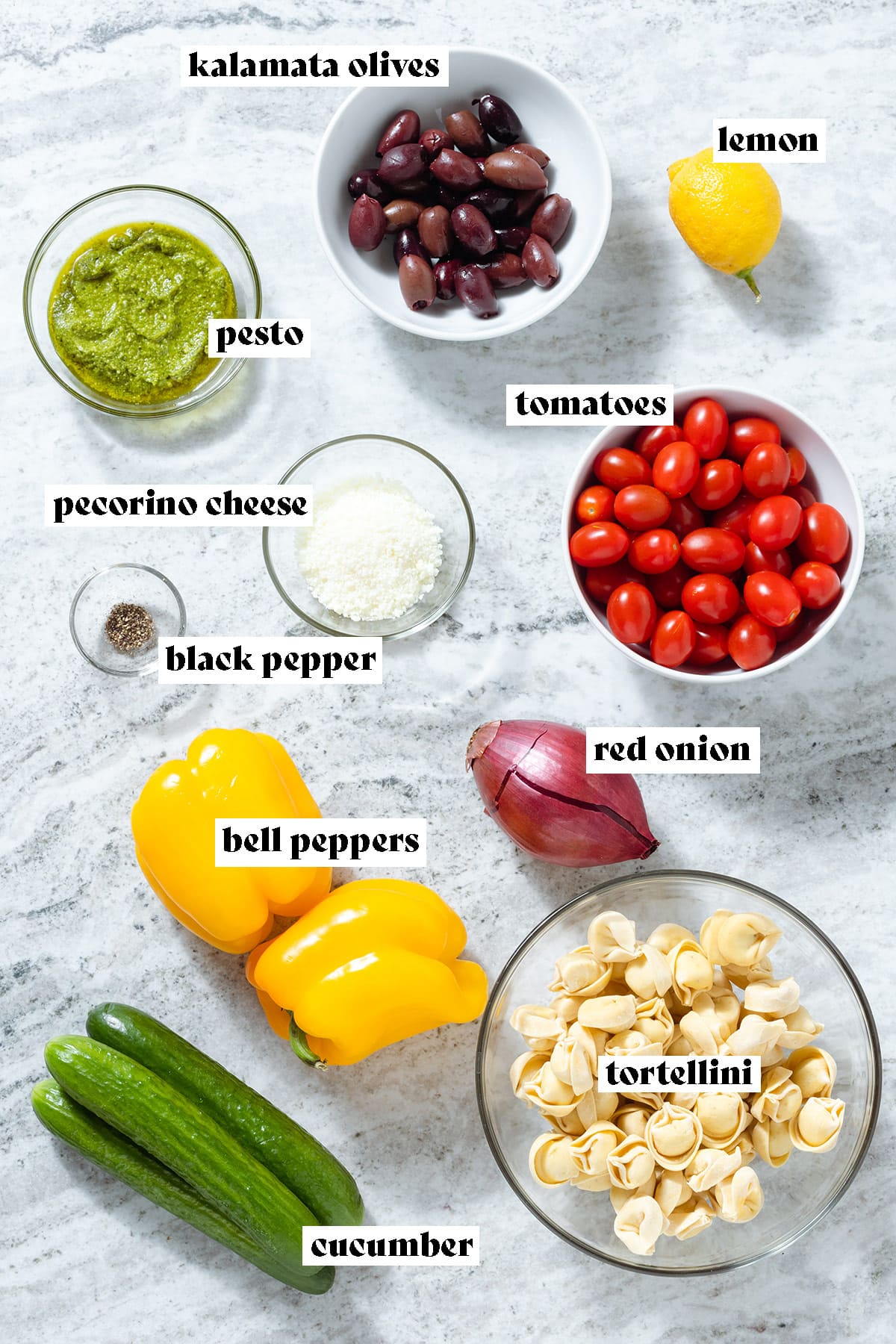 Cherry tomatoes, cucumbers, bell peppers, tortellini, and other ingredients laid out on a grey background with text overlay.