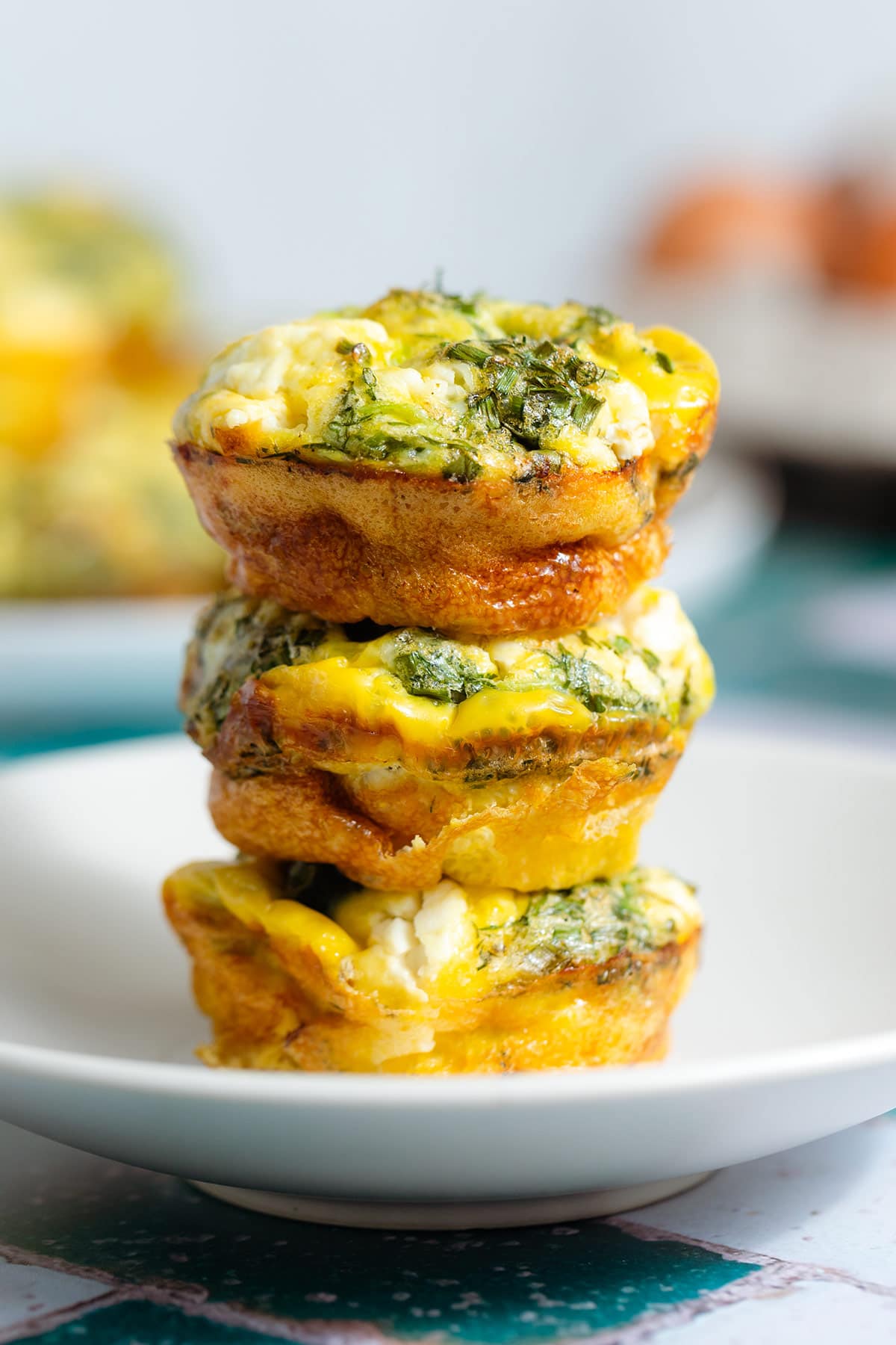Zucchini egg muffins stacked on top of each other showing the golden crispy sides.