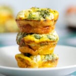 Zucchini egg muffins stacked on top of each other showing the golden crispy sides.