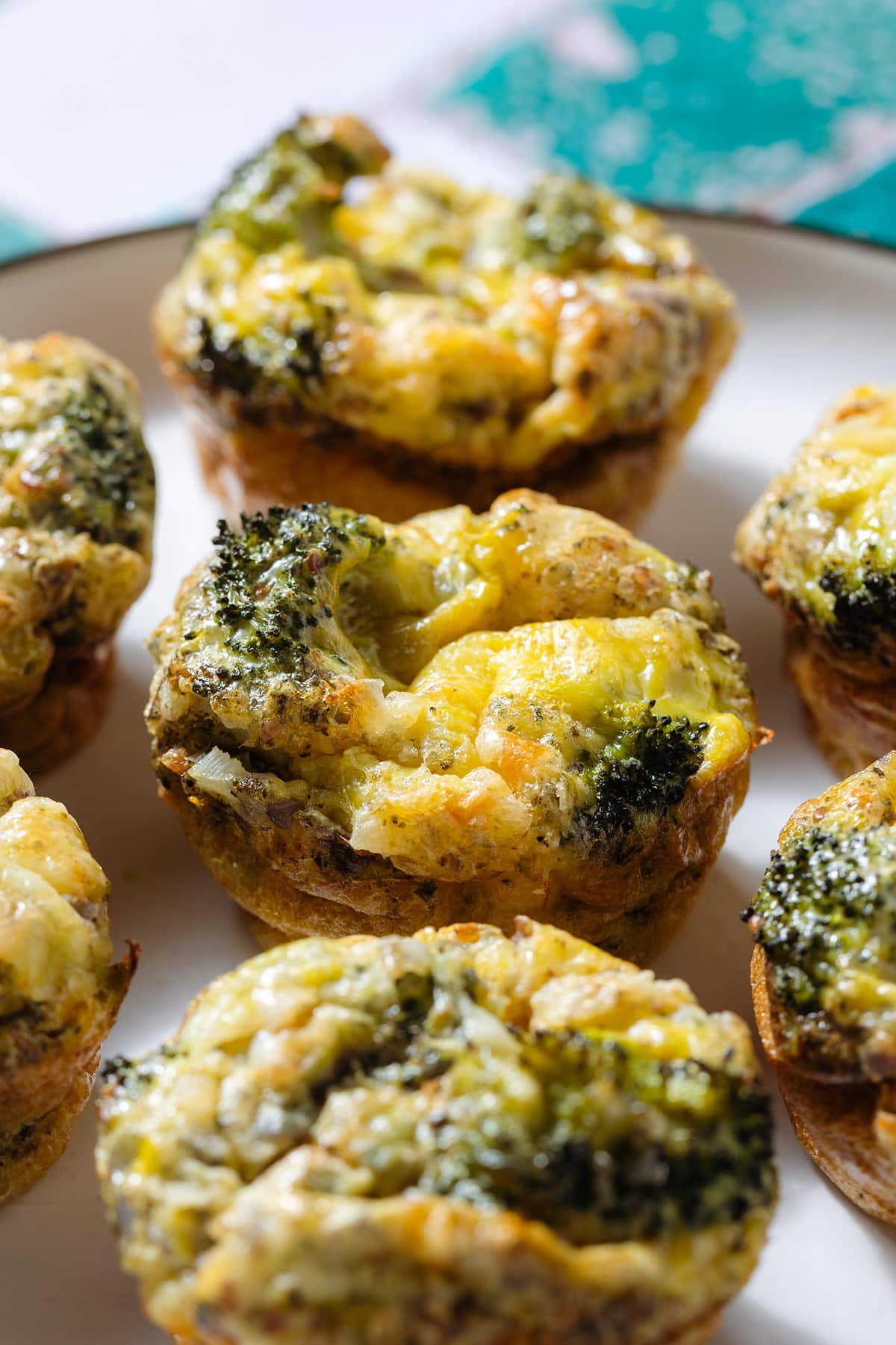 Cheesy broccoli egg muffins ona white plate.