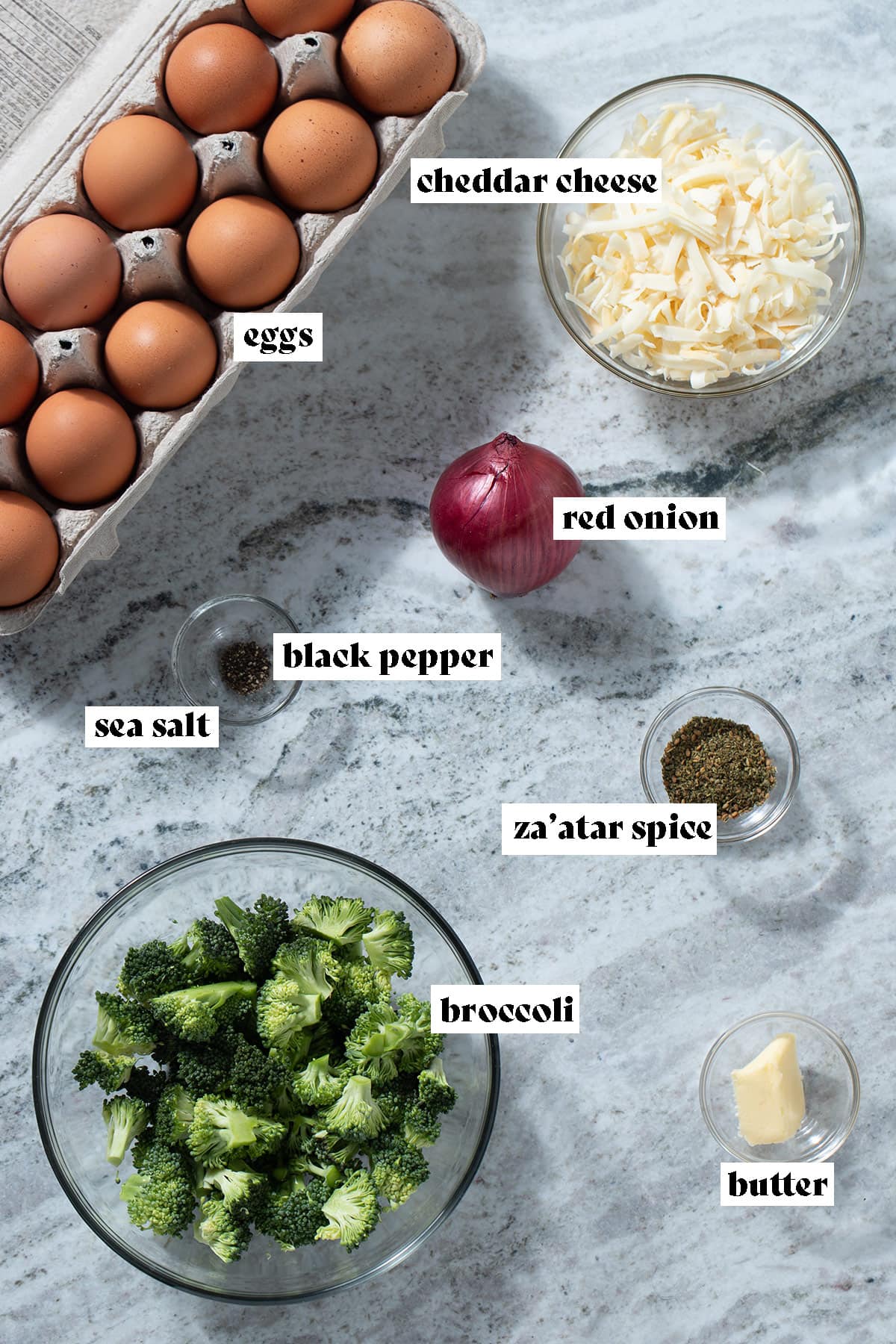 Ingredients like eggs, broccoli, red onion, and cheese laid out on a grey background with text overlay.