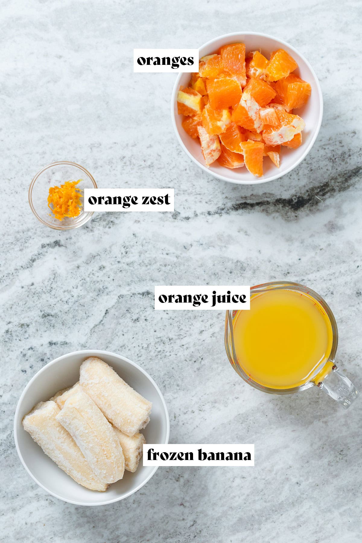 Fresh orange, bananas, orange zest, and orange juice in small bowls.