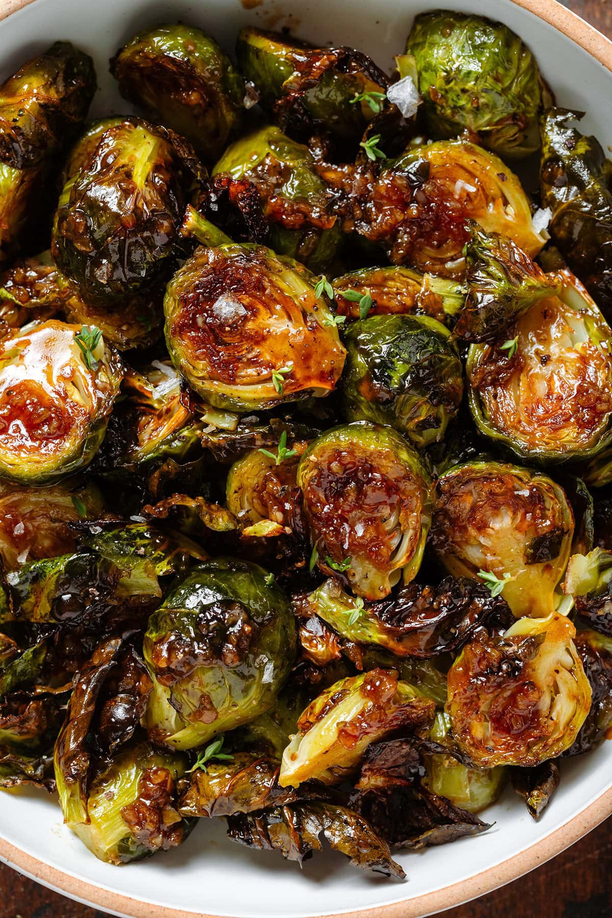 Crispy saucy golden brussels sprouts with sprinkled with salt flakes and fresh thyme.