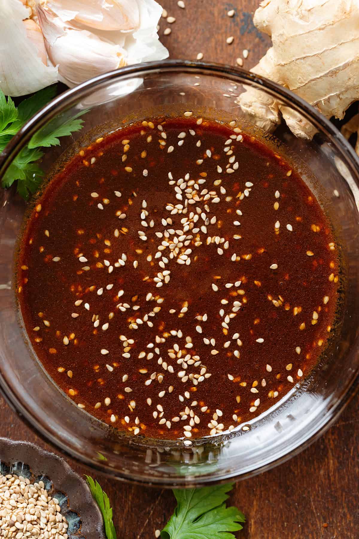 Dark brown miso dressing in a small glass bowl garnished with sesame seeds.