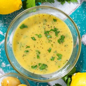 Bright yellow vinaigrette in a small glass bowl garnished with fresh parsley and black pepper.