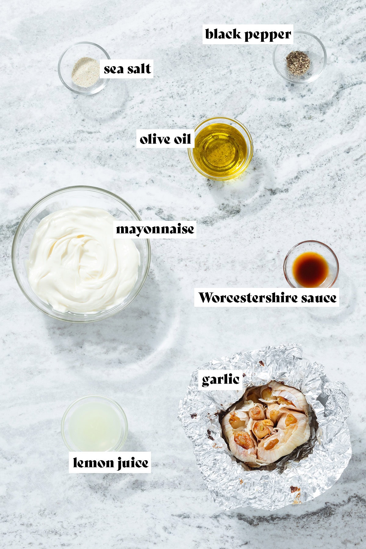 Ingredients like roasted garlic, mayonnaise, lemon juice, and olive oil all laid out in small bowls with text overlay.