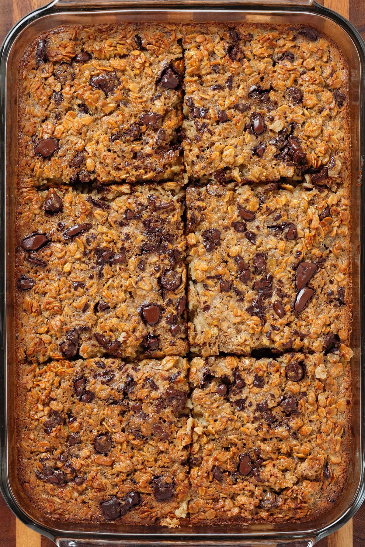 Golden chocolate chip baked oatmeal in a large glass baking dish sliced into 6 squares.