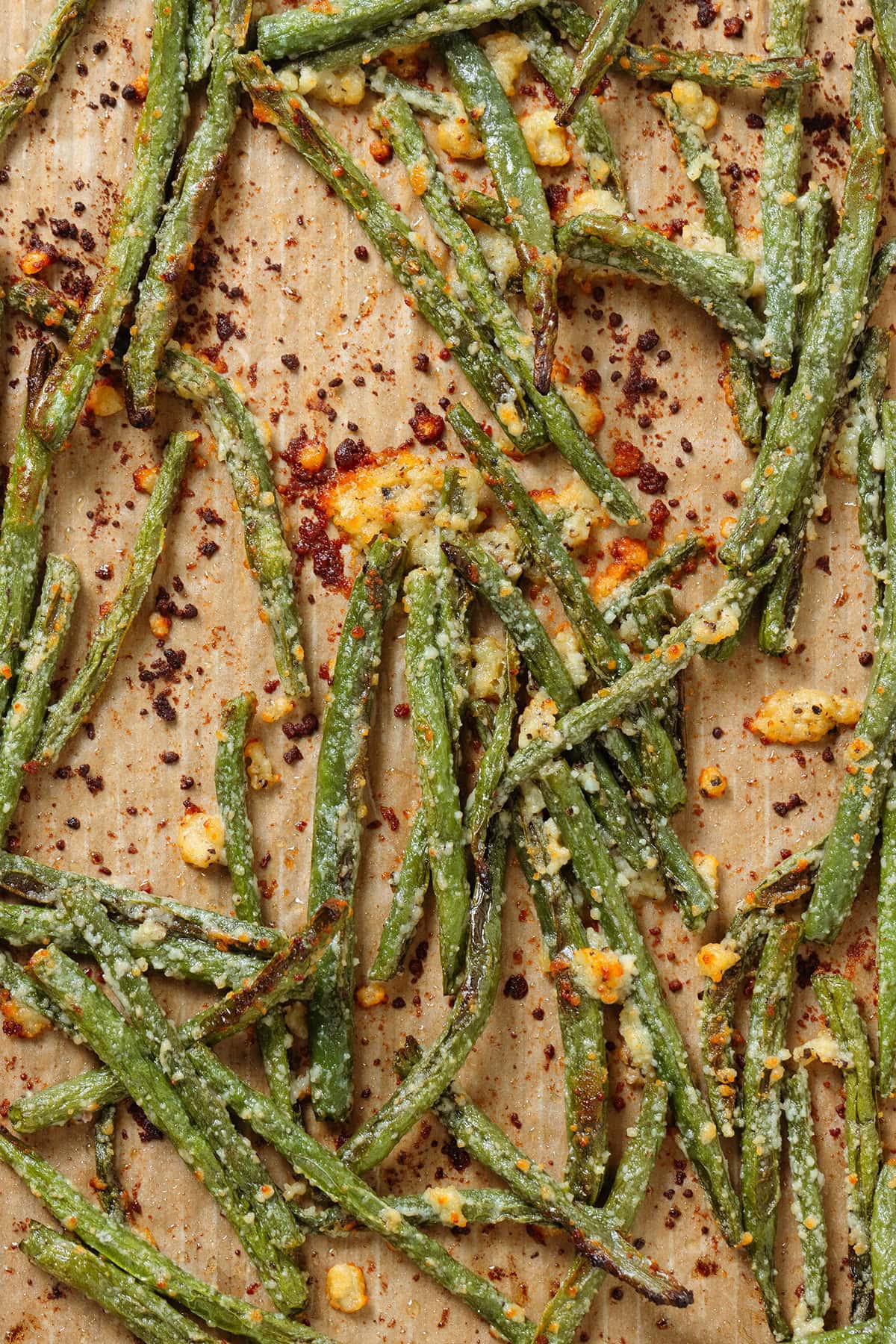 Roasted green beans with parmesan on parchment paper lined baking sheet.