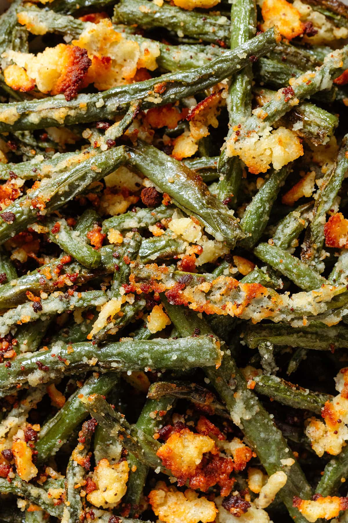 Golden roasted green beans with crispy parmesan on top.