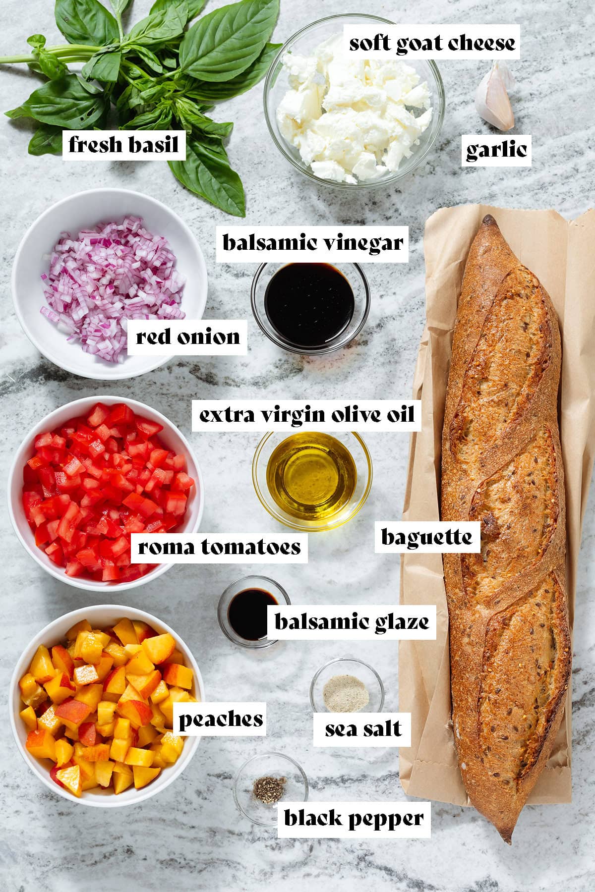 Ingredients like a whole baguette, fresh basil, spices, and diced veggies like tomatoes, red onion, and peaches in small bowls.